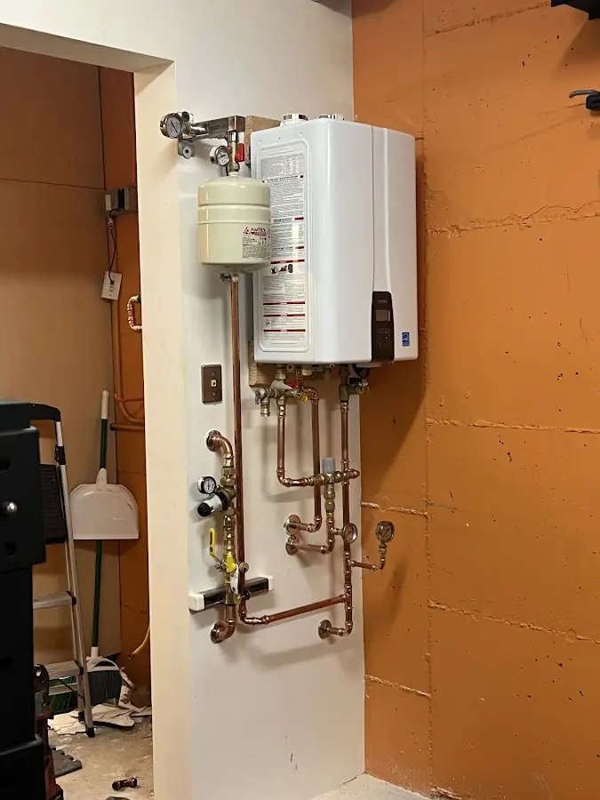 Plumbing technician inspecting water heater connections in Fabens